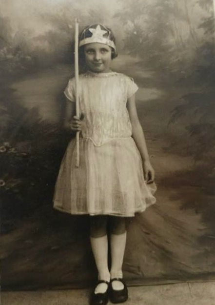 Auntie Eva in a party dress with a crown on her head and carrying a star