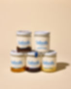 5 small jars filled with yogurt and toppings stacked on top of each other on a beige background