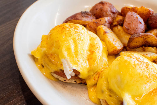 Eggs Benedict with potatoes, closeup shot on plate, ready to enjoy Ball Square Cafe