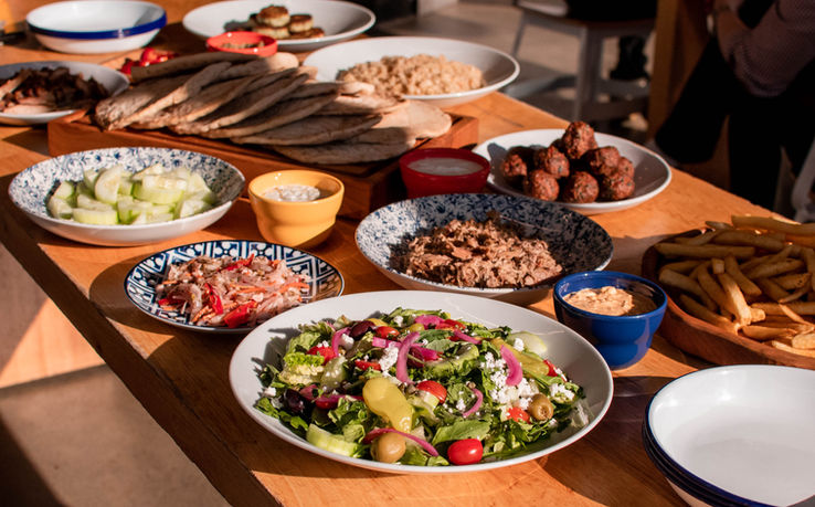 Wooden table filled with colorful dishes of all sizes plated with an assorted of food