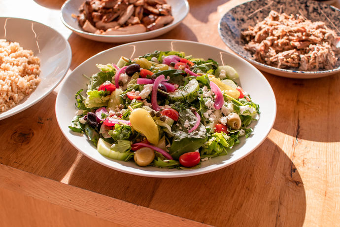 Large white bowl filled with colorful greek salad with fresh vegetables