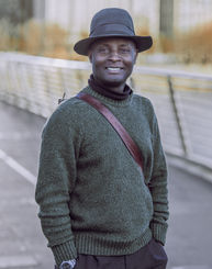 In this captivating portrait, meet a black man exuding charm and elegance as he poses on the iconic Golden Jubilee Bridge in London. 