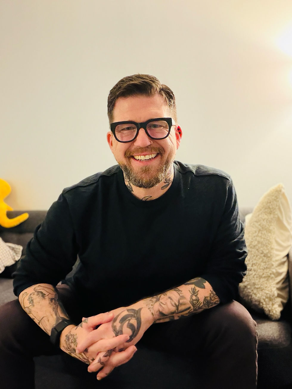 Smiling Jason Heisserer with glasses and tattoos.