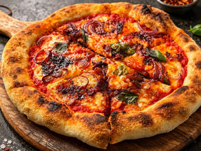 Home oven baking steel pizza with spicy nduja, cheese, red onions and basil on a wooden board, on a dark rustic table