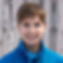 Kathleen Koford - a smiling woman with a pixie cut against a rustic wooden background.