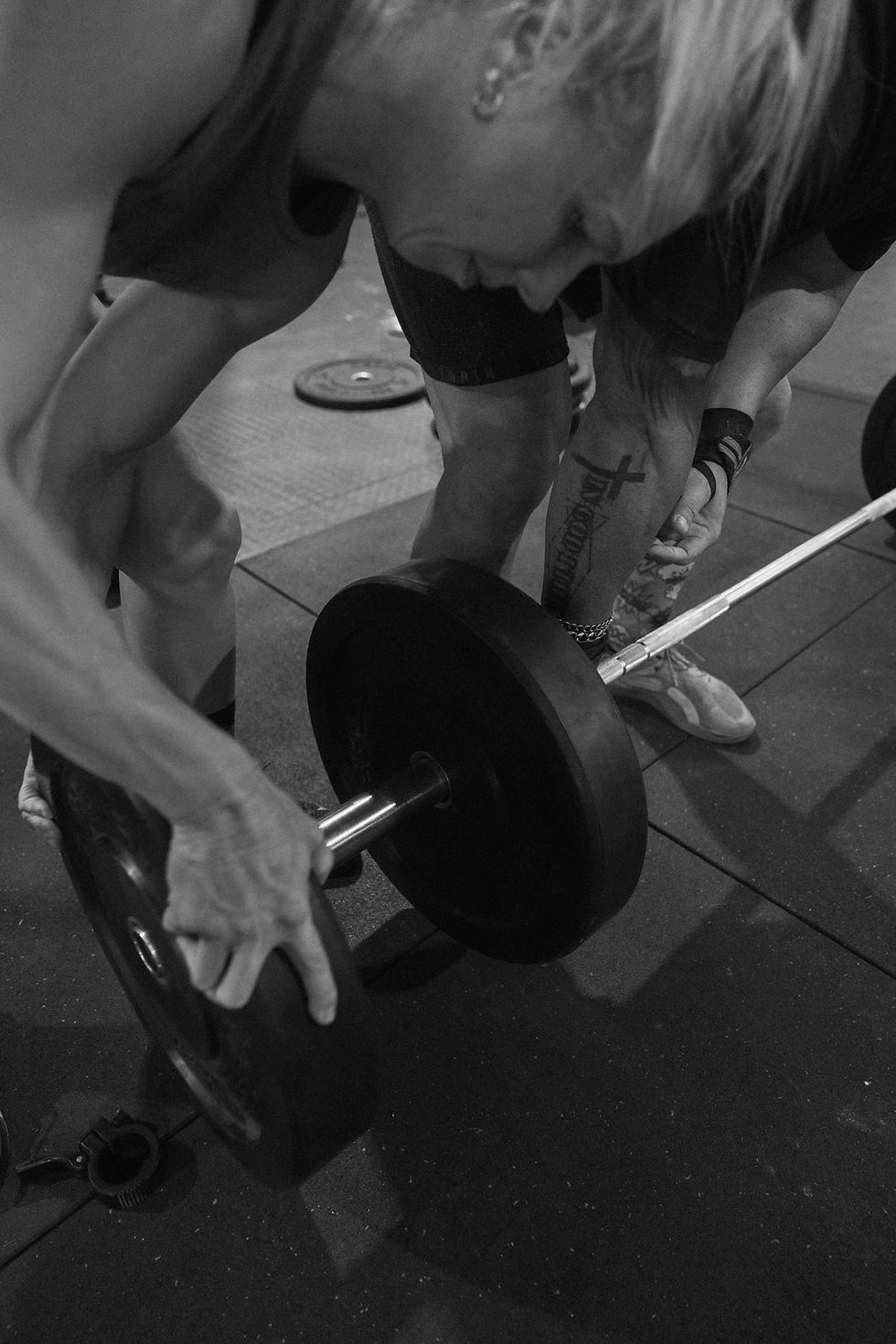 People loading weights onto a barbell at a fitness centre.