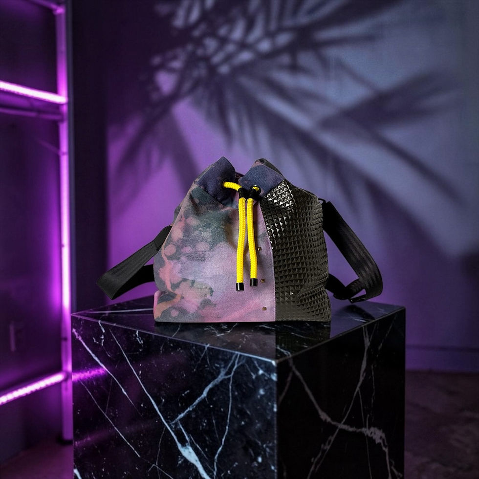 Thumbnail: Eine Beuteltasche mit Kordelzug, die ein geteiltes Design aufweist: eine Seite mit einem gedämpften rosa-grauen Batikmuster u