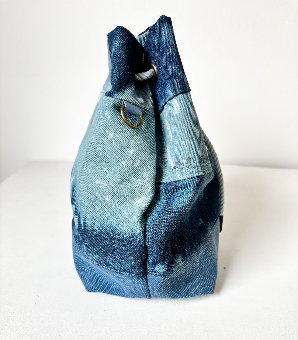 Thumbnail: Eine Bucket Bag aus gebatiktem Jeansstoff und einem Boden aus Canvas, steht vor einem weißen Hintergrund. Man sieht die Tasch