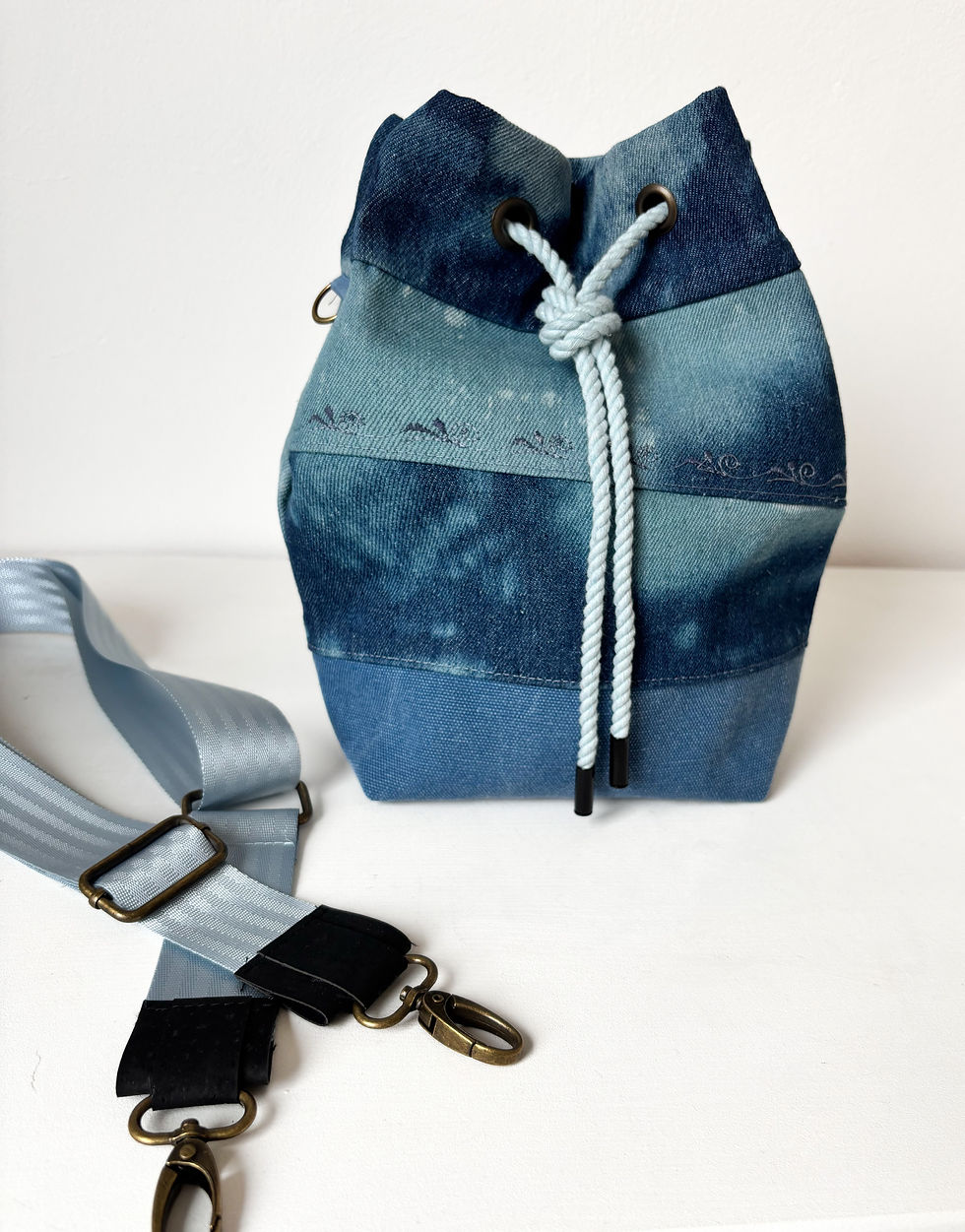 Thumbnail: Eine Bucket Bag aus gebatiktem Jeansstoff und einem Boden aus Canvas, steht vor einem weißen Hintergrund.