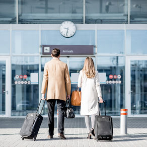 A stylish couple with luggage arrives at a modern airport terminal, ready for their luxury European holiday. The image illustrates seamless travel planning with Luxury Dream Holidays.