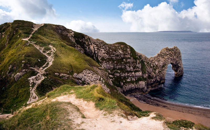 Durdle Door, an iconic natural arch, marks one of the many breathtaking views along the Dorset Rough Riders' coastal trails, where cycling meets the geological wonders of the Jurassic Coast.
