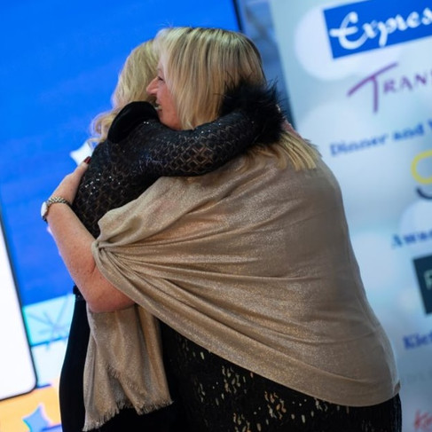 Claire from Luxury Dream Holidays sharing a warm congratulatory hug on stage after winning the Most Improved Agent award at the AITO Kickstart event.