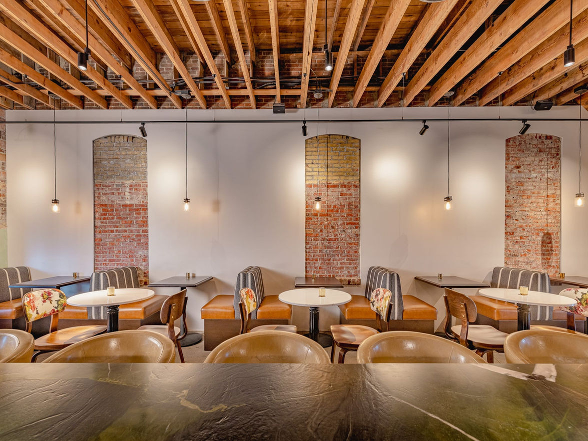 Booth seating wall inside Myrtle’s Emerald Lounge with exposed brick, pendant lights, and wood ceiling — available for private dining, wedding receptions, and events