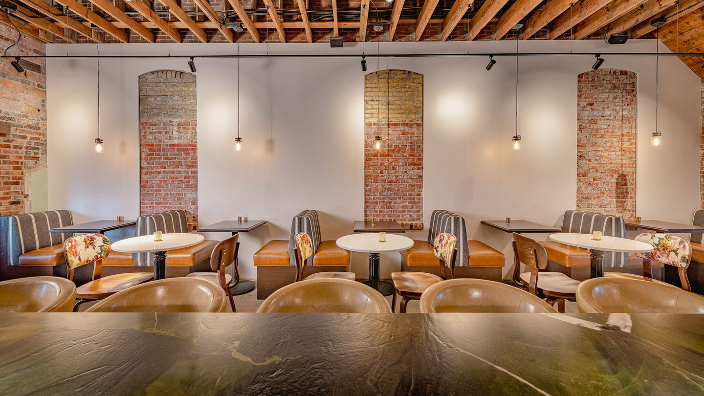 Booth seating wall inside Myrtle’s Lounge with exposed brick, pendant lights, and wood ceiling — available for private dining, wedding receptions, and events