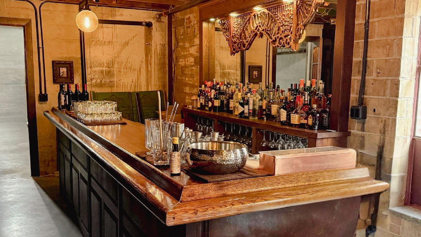 Vintage cocktail bar setup inside Myrtle’s hidden Speakeasy, featuring ornate woodwork, spirits, and warm ambient lighting