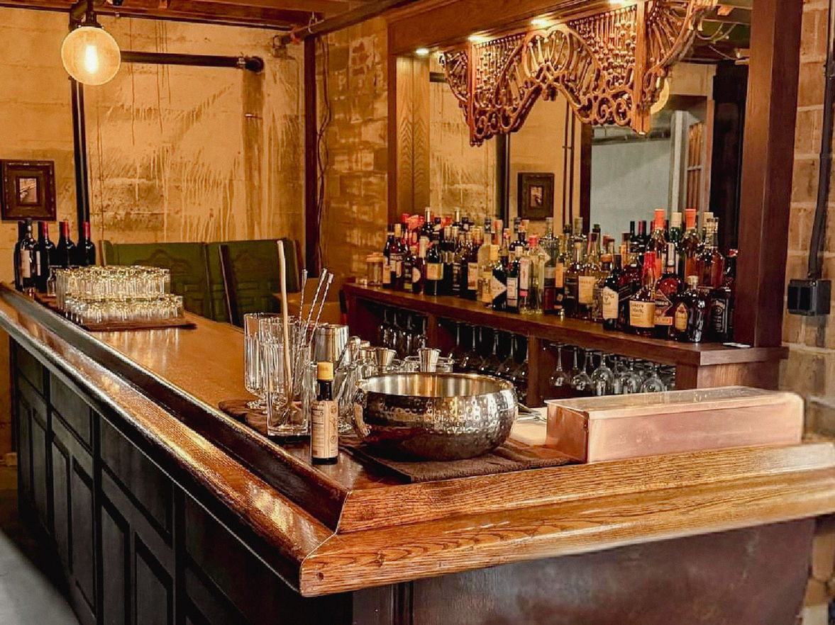 Vintage cocktail bar setup inside Myrtle’s Fur Vault hidden Speakeasy, featuring ornate woodwork, spirits, and warm ambient lighting