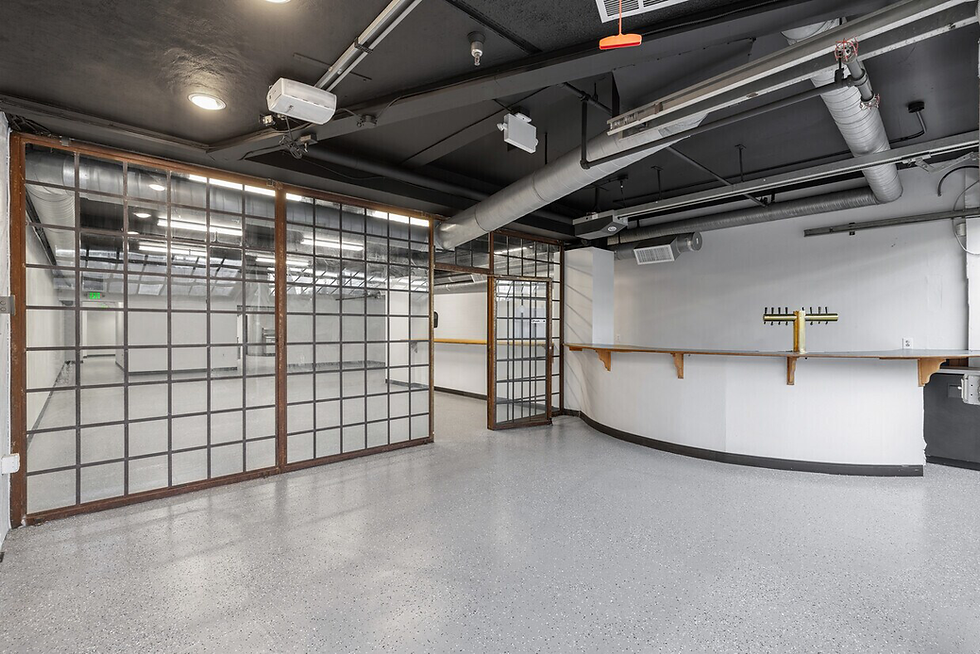 Commercial interior of a vacant restaurant space in Hillcrest featuring concrete flooring, track lighting, exposed ceiling ductwork, and built-in wall counters.