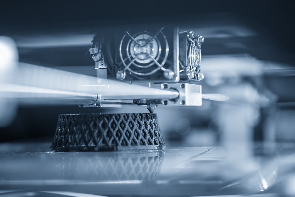 Monocolour photo of a 3D printer building a small support structure