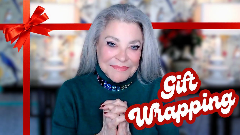 Lois Mills smiles warmly, wearing a chic green sweater with a sparkling jeweled neckline. The background features festive holiday decor, softly blurred to enhance focus on Lois. A bright red ribbon frames the image with the text 'Gift Wrapping' written in bold, festive font, adding a holiday touch to the scene.