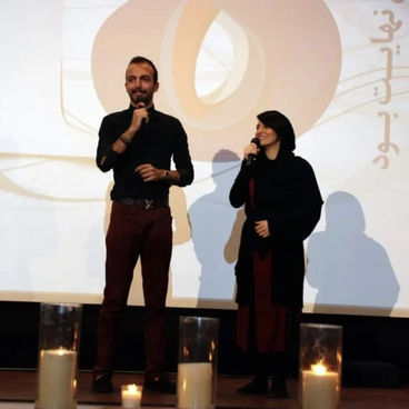 Amir Noferesti celebrating the 18th anniversary of Behnam Daheshpour Charity Organization. The image shows Amir smiling, surrounded by fellow volunteers and beneficiaries, highlighting the joyous atmosphere of the celebration. The background includes banners and decorations marking the anniversary, emphasizing the spirit of community and the significant impact of the charity's work over the years.