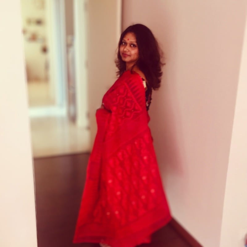 Woman in a red saree standing in a hallway. Pallavi Roy Dutta