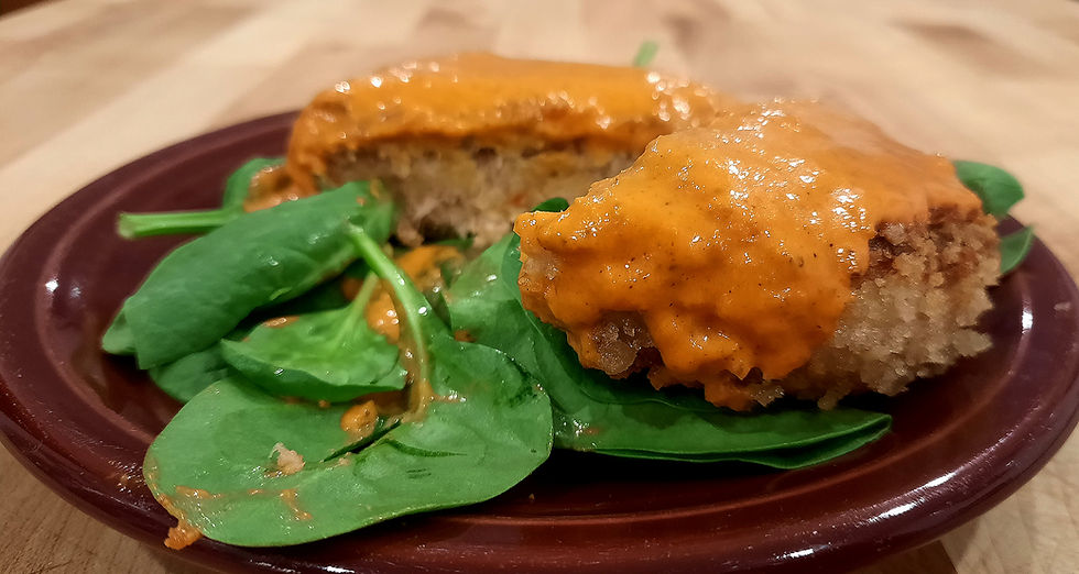 Crab cake with roasted red pepper sauce on a bed of fresh spinach