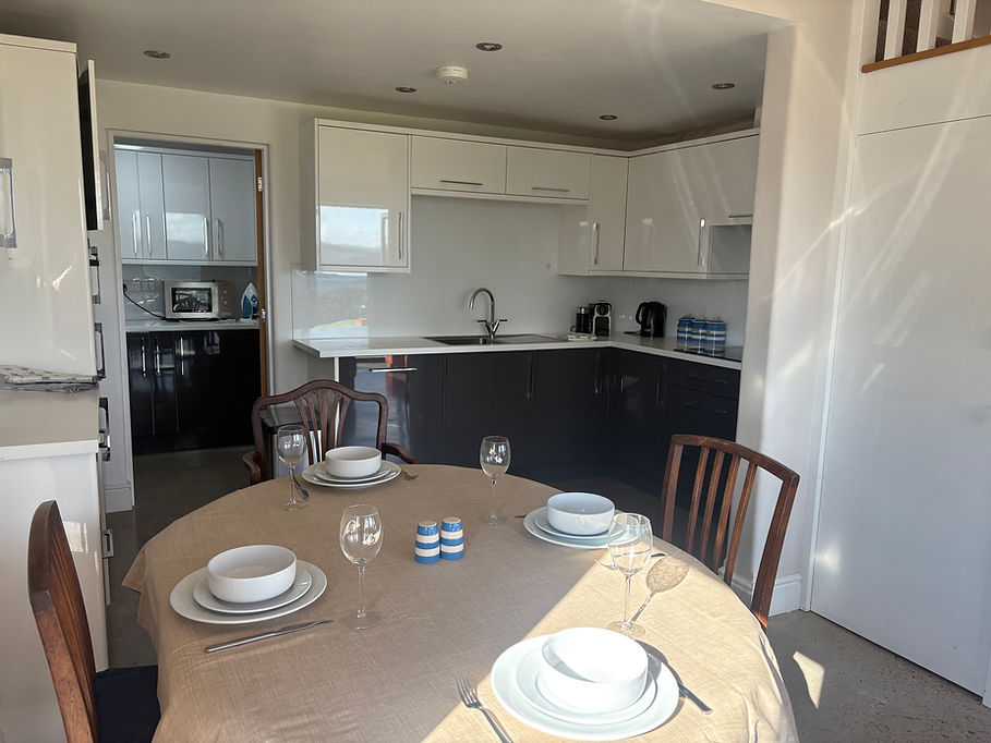 A bright, open-plan kitchen with a dining table set for meals, featuring modern appliances and a clean, comfortable layout