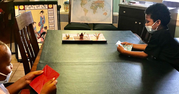 children learning how to fold paper to create an origami crane