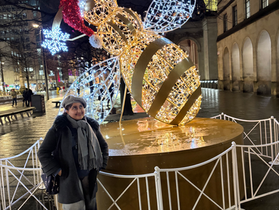 A girl standing next to a bee statue at Christmas