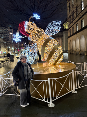 A girl standing next to a bee statue at Christmas