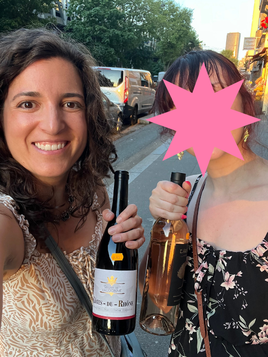 Lisa and friend each carrying a bottle of French wine down the street on the way back to their hotel