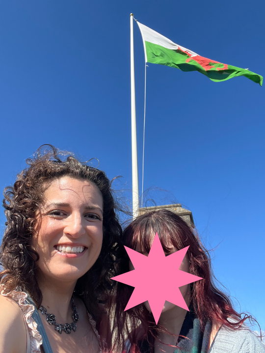 Lisa and friend with a Welsh flag behind them