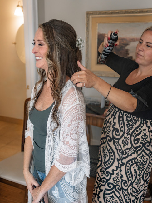 Bride smiling while getting her hair styled on wedding morning, showcasing trusted beauty vendors in Calgary wedding planning