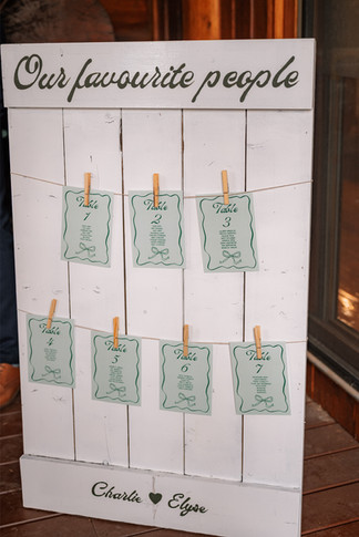 Custom seating chart display with table cards clipped to a wooden board as part of Calgary wedding planning décor.