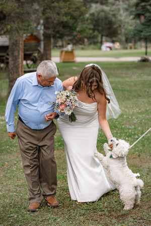 Bride and father sharing a sweet moment with family dog before ceremony begins