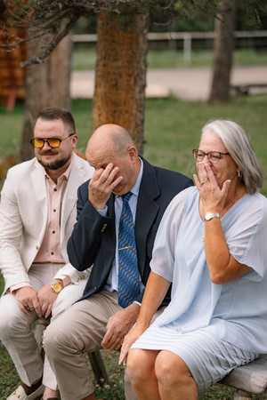 Emotional wedding guests wiping away tears during outdoor ceremony at Bragg Creek wedding at Folk Tree Lodge