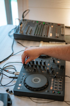 Wedding DJ adjusting sound mixer and audio equipment at an indoor reception as part of Calgary wedding planning details.