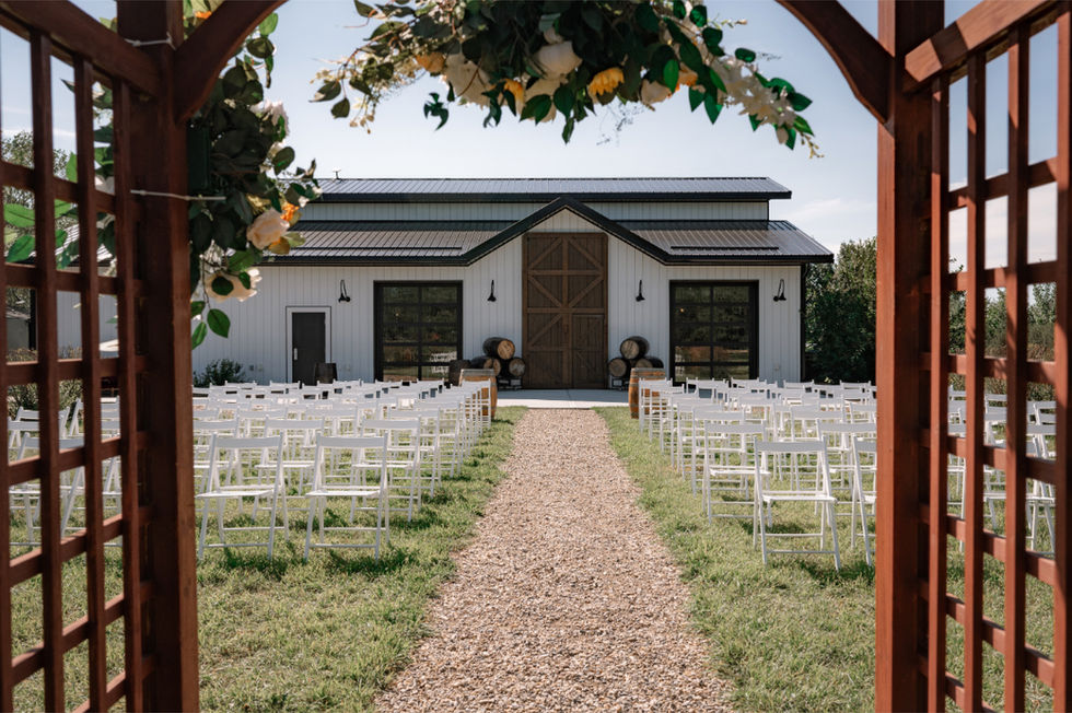 Outdoor ceremony setup with white chairs and barn backdrop framed by floral arch at Calgary small wedding venues