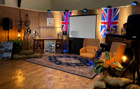 Photo of lit stage decorated in World War 2 era props with projector screen, british flags, camera lighting and handmade animation figurines