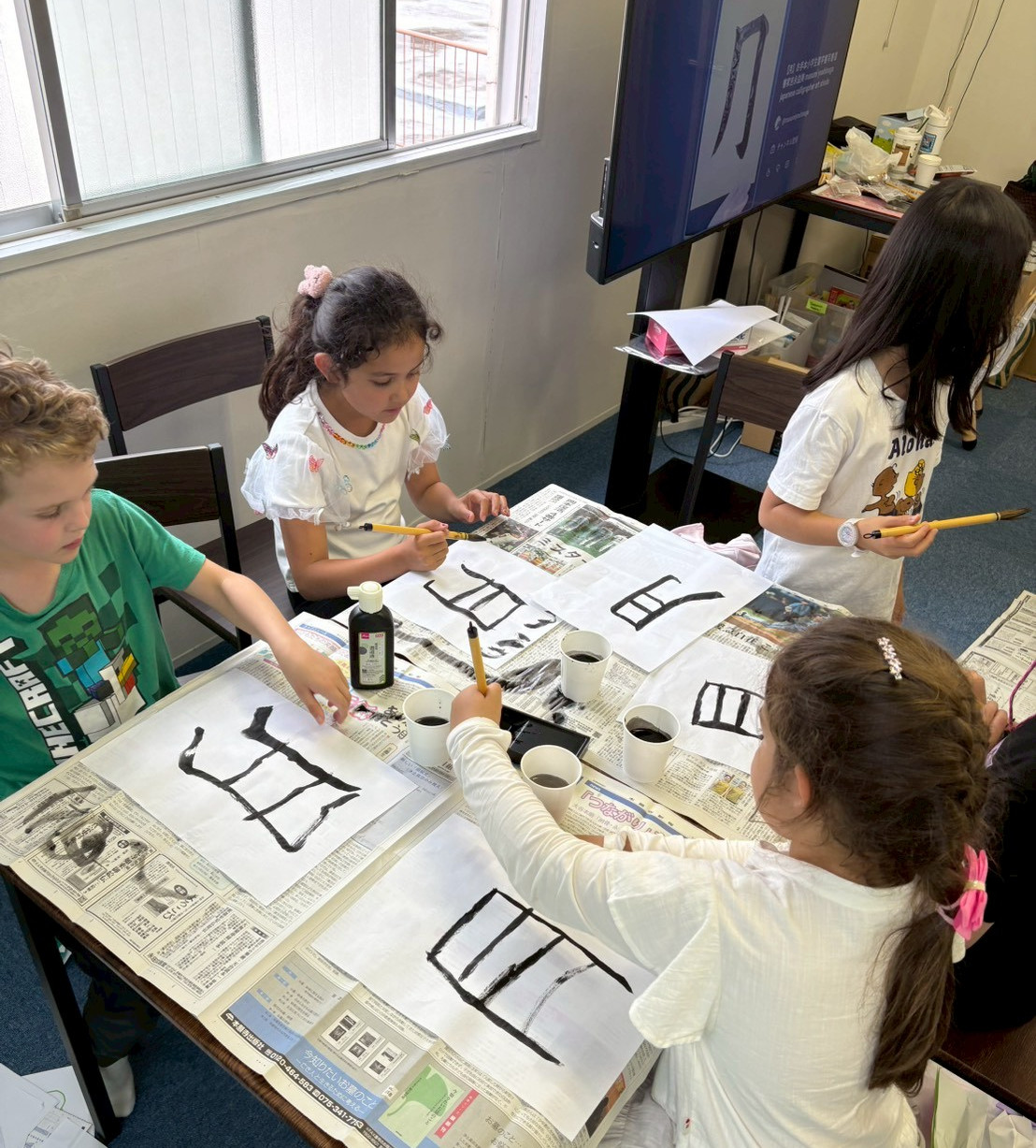 Children practising Japanese calligraphy with brushes and ink at Elev8 camp.