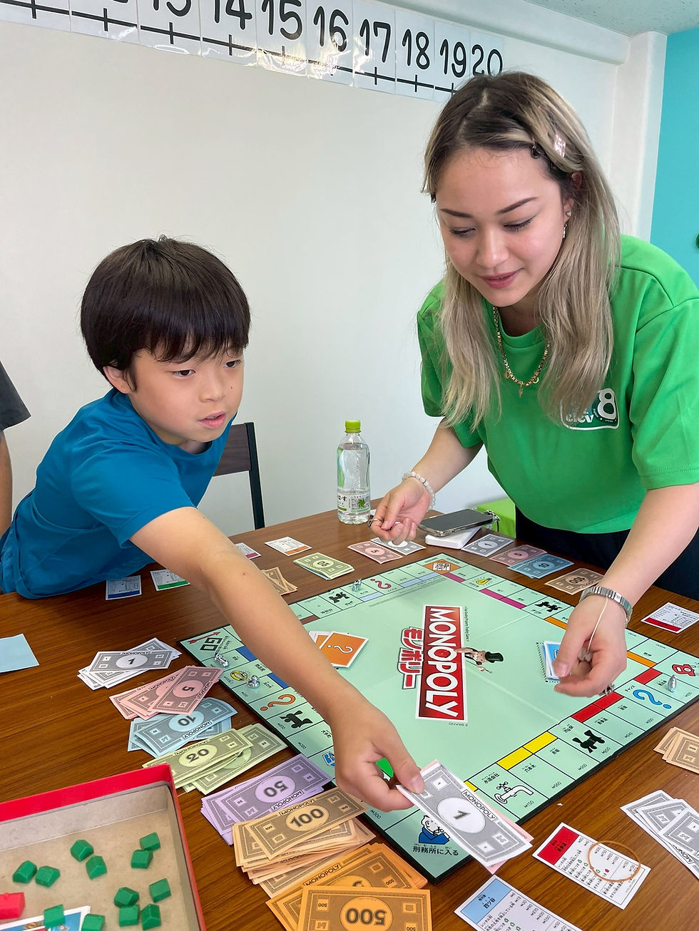 Mia, a multilingual English teacher at Elev8, playing Monopoly with students during summer camp to encourage communication and critical thinking.