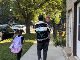young girl walking to the first day of school with her family.