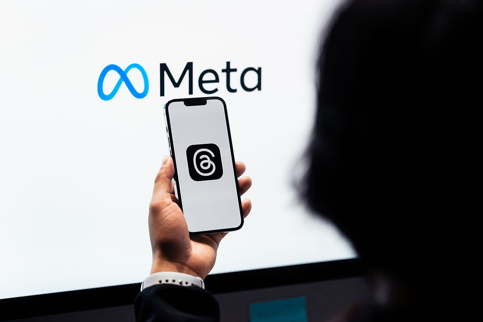 Silhouette of a person holding a mobile phone in front of an illuminated META sign