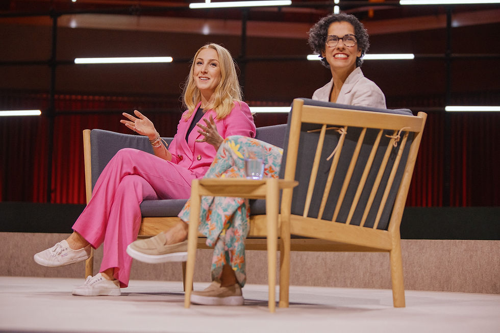Rachel Arthur, wearing a bright pink suit, speaks passionately about sustainable fashion while seated on stage during a panel discussion.