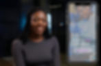 Dr Giovannie Jean-Louis smiling in an interview setting, with a mobile screen displaying the PROBr app beside her.