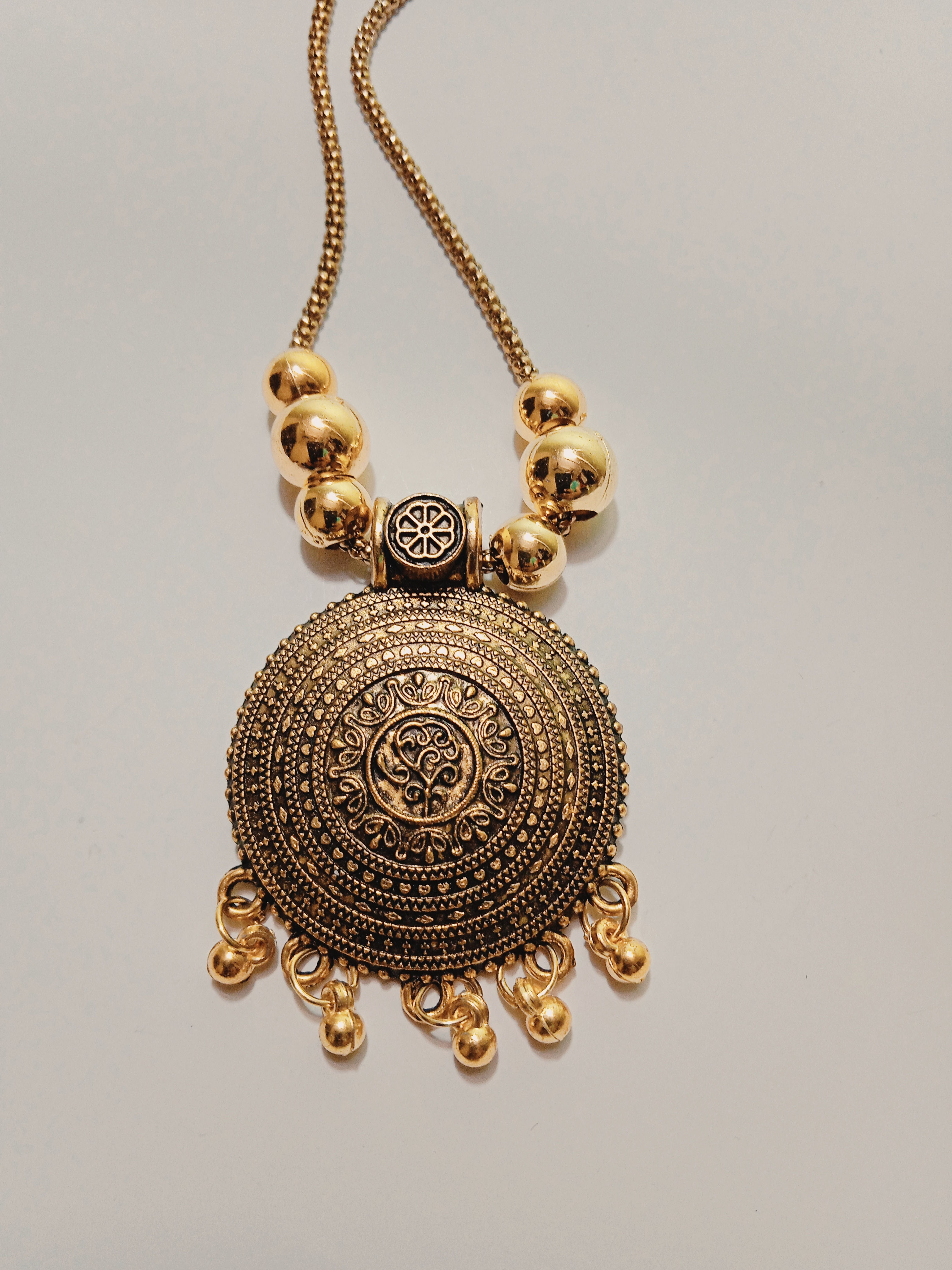 Okhali - Golden Oxidised Antique Round Pendant with Ghungroo and snake chain