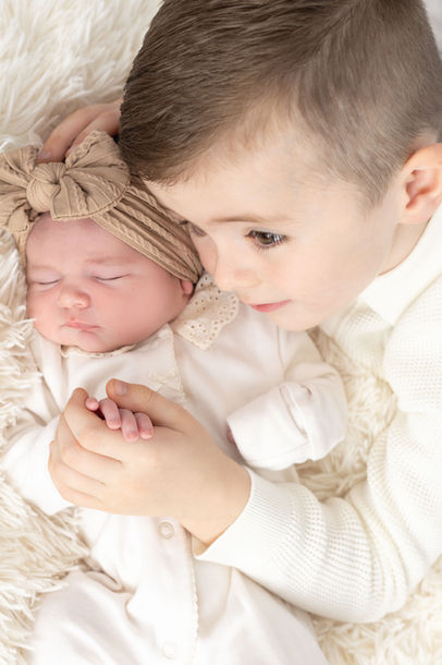 Newborn and sibling photo session image of a little boy cuddling his newborn Sister. Photo taken in Essex photography studio Photo Creative UK