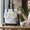 Thumbnail: Woman with floral canvas bag sitting at a table near a coffee cup.