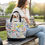 Thumbnail: A woman sitting with a colorful coin/card/cats canvas bag on a bench in a park.