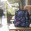 Thumbnail: Hand reaching into blue backpack with pink dragonfly print on outdoor cafe table AWESOMEROSE'S